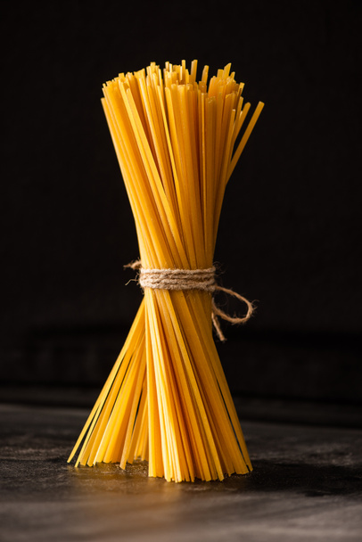 tied uncooked Italian spaghetti isolated on black - Foto, afbeelding