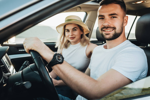Feliz pareja joven sentada dentro de su coche disfrutando de un viaje por carretera, viaje y aventura Concepto - Foto, imagen