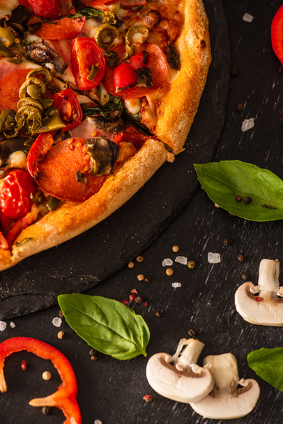 close up view of delicious Italian pizza with vegetables and salami on black background - Фото, изображение
