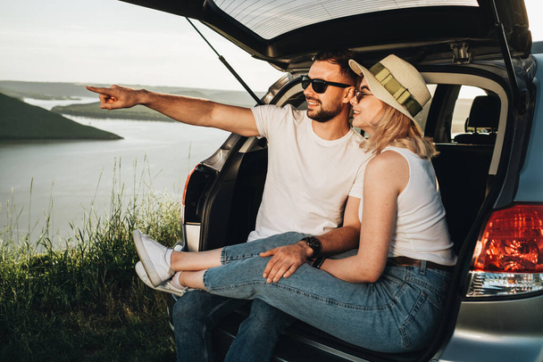 Uomo e donna rilassante all'interno del bagagliaio auto godendo week-end viaggio su strada, viaggio e avventura concetto - Foto, immagini