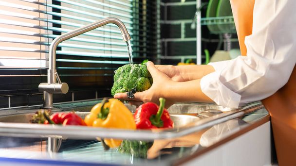Mulher mãos lavar Legumes para Preparação de salada vegan na bancada perto de afundar em uma cozinha moderna, Conceito de comida saudável caseiro - Foto, Imagem