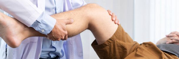 физиотерапевт-реабилитационный врач консультирует физиотерапевта, оказывая физиотерапевтическое лечение колена с пациентом в физиотерапевтической клинике или больнице - Фото, изображение