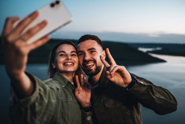 Dos jóvenes y felices viajeros haciendo selfies al atardecer junto al cañón - Foto, imagen