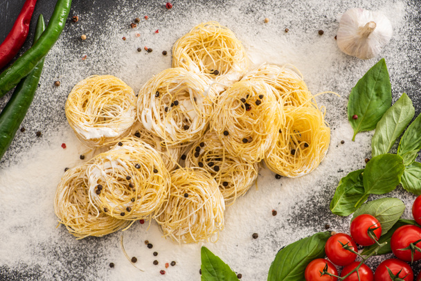 top view of raw Capellini pasta with vegetables, spices and flour - Foto, imagen