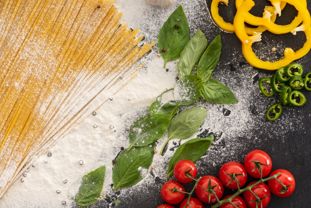 widok z góry surowego spaghetti z warzywami, przyprawami i mąką - Zdjęcie, obraz