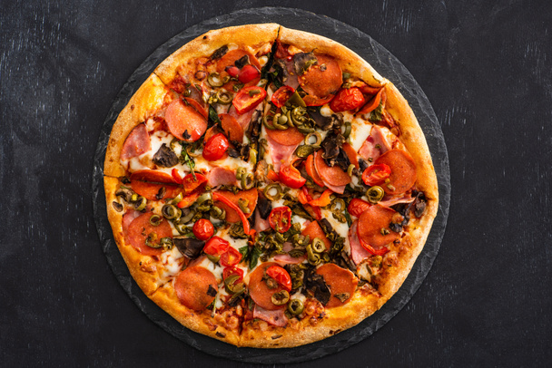 top view ízletes olasz pizza szalámi fekete fa háttér - Fotó, kép