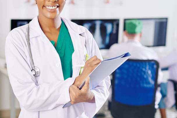 Обрізане зображення чорної жінки-лікаря з красивим зубним посміхненим документом в руках
 - Фото, зображення