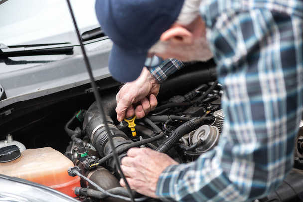 Araba tamircisi bir arabanın motorunu kontrol ediyor. - Fotoğraf, Görsel