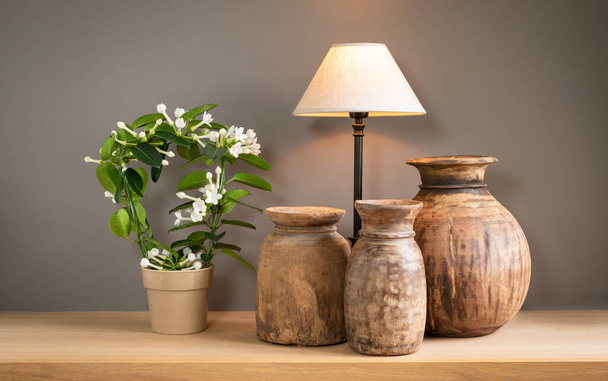 Salón decorativo bodegón con lámpara eléctrica, floreciente planta Stephanotis y viejas jarras de madera. Casa concepto interior. - Foto, imagen
