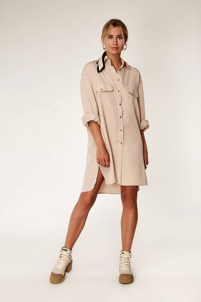 Beautiful sexy elegance woman skin tan body fashion model glamour pose wear trend casual clothes party summer beige long shirt dress collection makeup hair style blond success accessory studio. - Photo, image