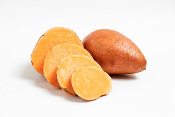Farm raised organic sweet potato tubers laid in composition on textured background. The edible tuberous root vegetable on table counter. Clean eating concept. Background, close up, flat lay, top view. - Fotó, kép