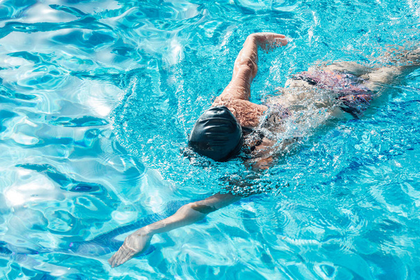 Mujer con gorra de natación y gafas nadando en una piscina - Foto, Imagen