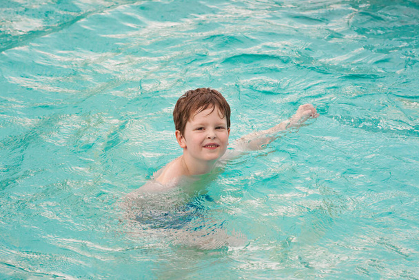 Boldog gyerek játszik az uszodában. Szórakozni kint a medencében a nyári napon. Szabadidő és úszás ünnepnapokon. Boldogság és öröm. - Fotó, kép