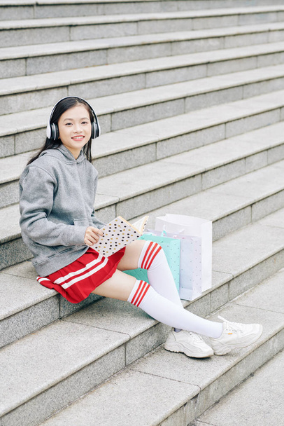 笑顔明るいアジアの女の子は買い物の後の手順で休憩,本を読んで、音楽を聴く - 写真・画像