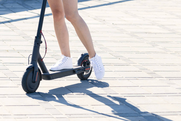 Gros plan des jambes d'une fille sur un scooter électrique - Photo, image