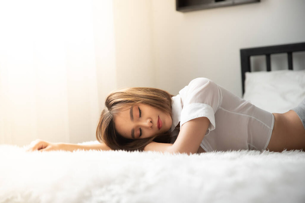 Προσεκτική νεαρή γυναίκα ξαπλωμένη στο κρεβάτι στο σπίτι - Φωτογραφία, εικόνα