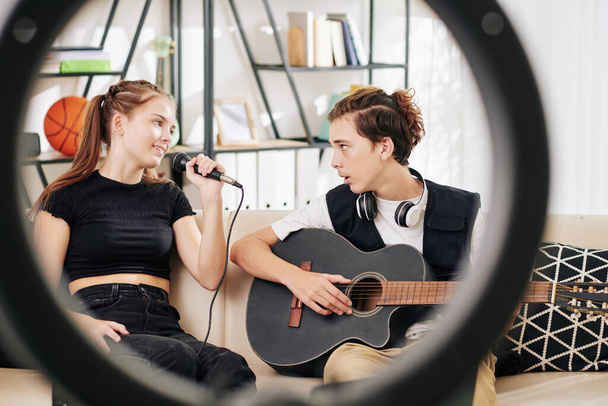 Stylový dospívající chlapec hraje na kytaru, když jeho sestra zpívá píseň v mikrofonu - Fotografie, Obrázek