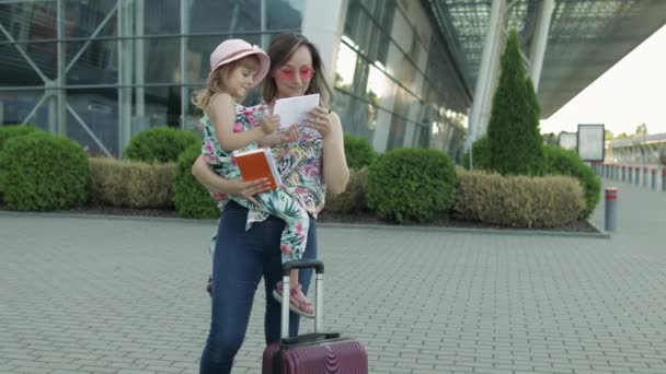Mère et fille près de l'aéroport. Les femmes ont des passeports et des billets en main. Vacances d'enfant et de maman - Séquence, vidéo