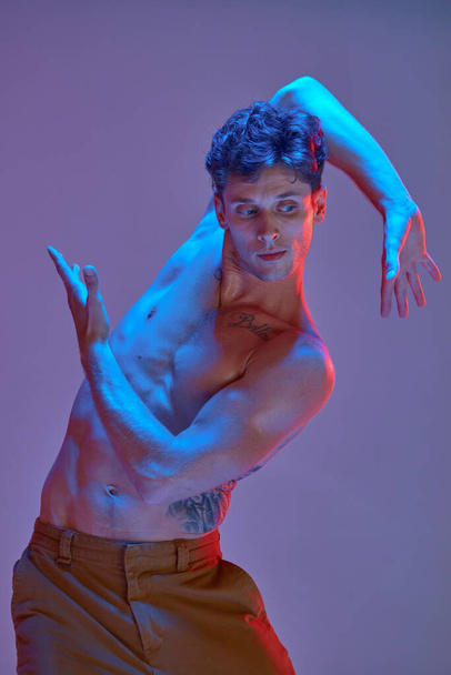 Cool young man dancing expressive dance without shirt in lilac neon light. Colorful dance school poster - Φωτογραφία, εικόνα