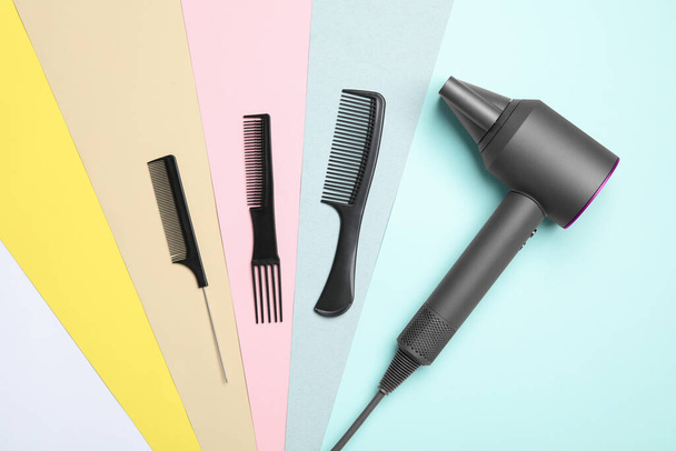 Hair dryer and different combs on color background, flat lay. Professional hairdresser tool - Foto, Imagen