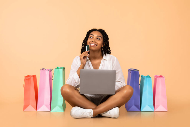 Dívka nakupování Online s notebookem sedí na béžovém pozadí - Fotografie, Obrázek