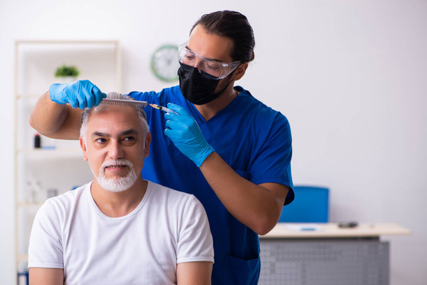 Anciano visitando joven doctor masculino en cono de trasplante de cabello - Foto, Imagen