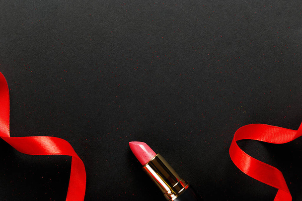 ピンクの口紅のトップビュー組成物。美容業界の製品コンセプト。ブラックのリボンでメイクアクセサリー。女性用口紅。女に考えがある。化粧品の属性 - 写真・画像