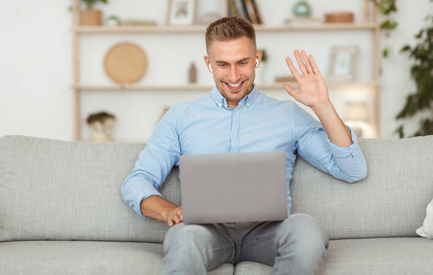 Ευτυχισμένος τύπος που χρησιμοποιεί φορητό υπολογιστή για βιντεοκλήση και χαιρετισμό - Φωτογραφία, εικόνα