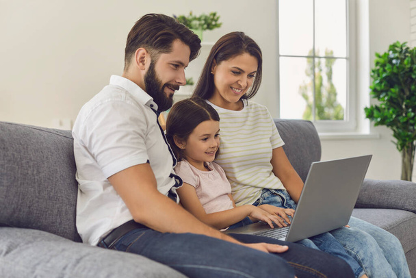 Happy family with laptop doing online shopping in the online store remotely at home. - Fotó, kép