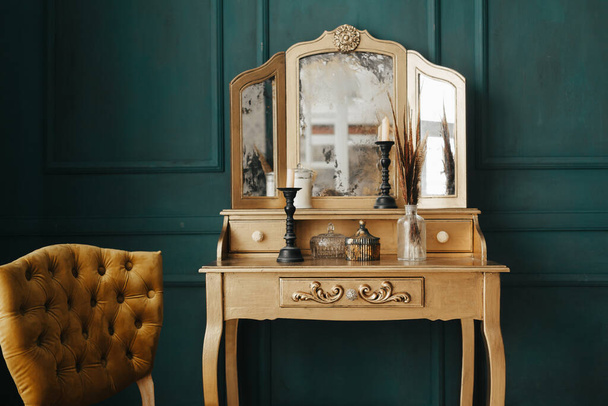 piękne vintage kolorowe wnętrze. klasyczny pokój z drewnianą podłogą zielone ściany z listwami, dressing złoty stół z lustrem ozdobione elementami, krzesło żółty - Zdjęcie, obraz