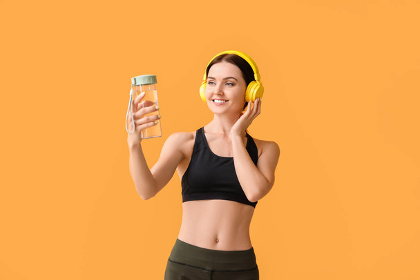 Sportliche junge Frau mit Flasche Wasser auf farbigem Hintergrund - Foto, Bild