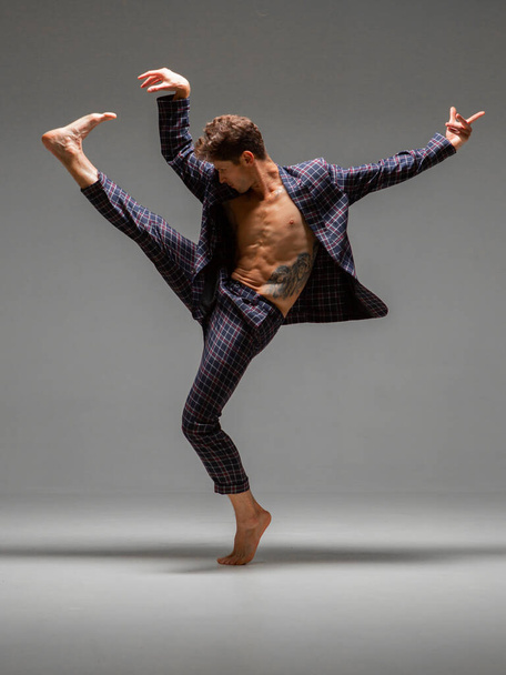 Cool young man dancer dancing expressive dance in suit in studio. Dance school poster. Dance lessons - Photo, image