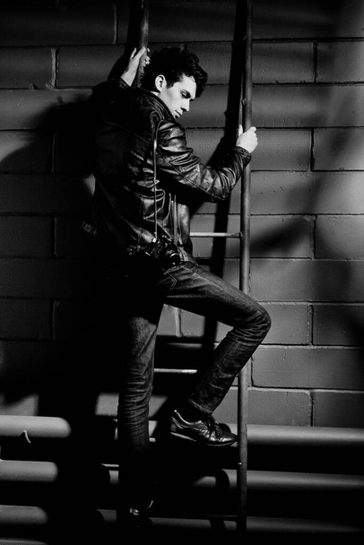 handsome model in leather jacket posing near wall - Foto, imagen