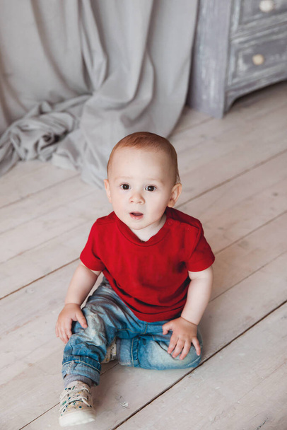 adorable baby boy on wooden floor in room - Fotó, kép