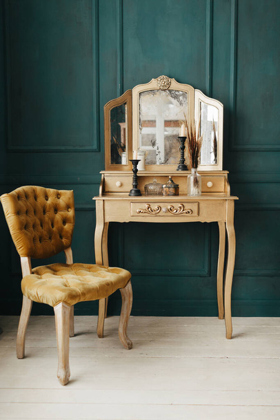 piękne vintage kolorowe wnętrze. klasyczny pokój z drewnianą podłogą zielone ściany z listwami, dressing złoty stół z lustrem ozdobione elementami, krzesło żółty - Zdjęcie, obraz