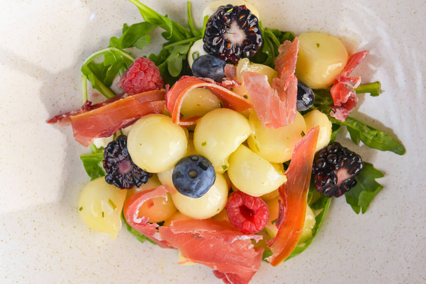 Salad of mixed summer berries. Seasonal summer salad with fruit and berries and Italian prosciutto meat. Concept for tasty and organic meal. - Фото, зображення