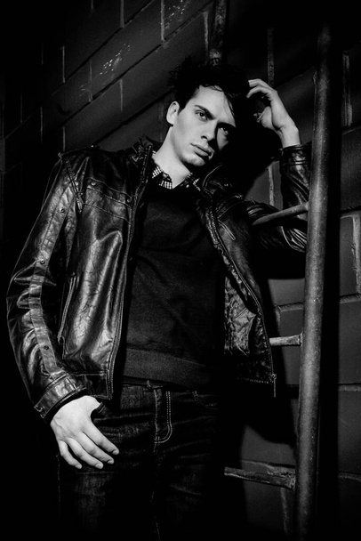 handsome model in leather jacket posing near wall - Foto, Bild