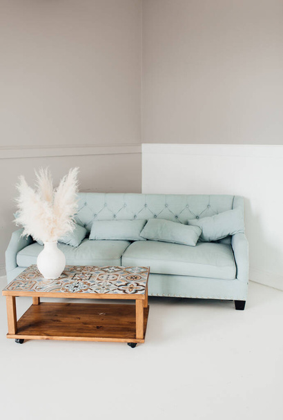 gemütliches warmes Wohnzimmer im skandinavischen Stil mit Holztisch und Minzsofa - Foto, Bild