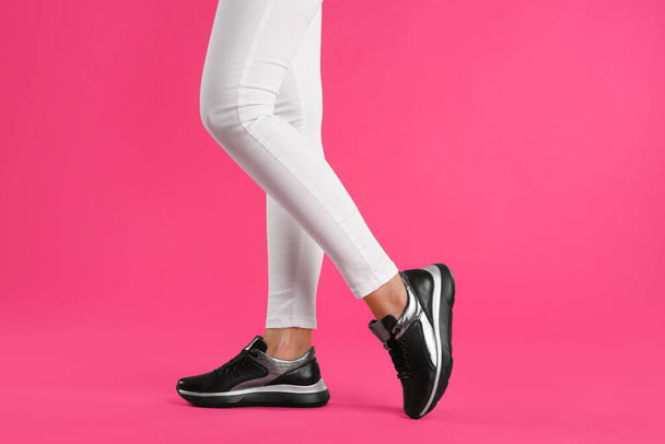 Woman wearing sneakers on pink background, closeup - Фото, изображение