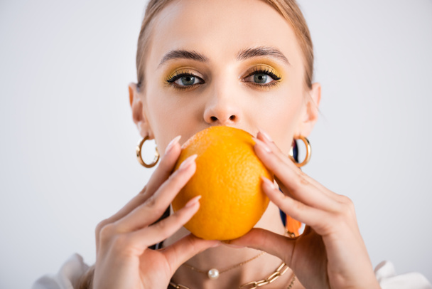 elegante mujer rubia posando con naranja en frente de la cara aislada en blanco - Foto, Imagen