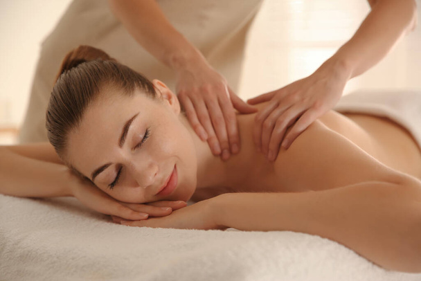 Young woman receiving shoulder massage in spa salon - Fotó, kép