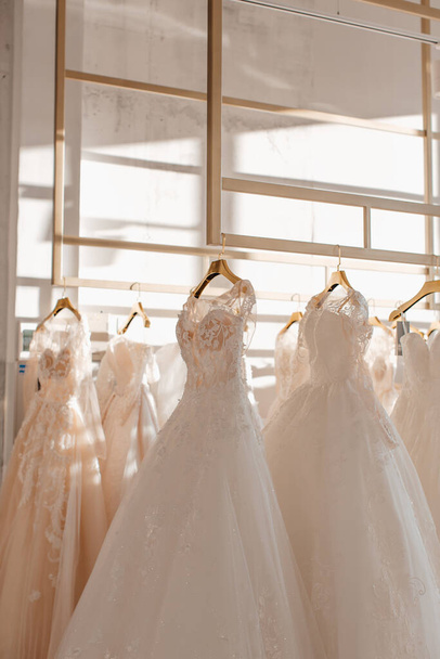 beautiful white wedding dresses on hangers in the store - 写真・画像