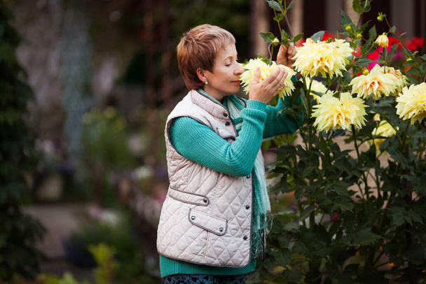 Yetişkin bir kadın evin arka bahçesinde bahçıvanlıktan emekli oldu. - Fotoğraf, Görsel