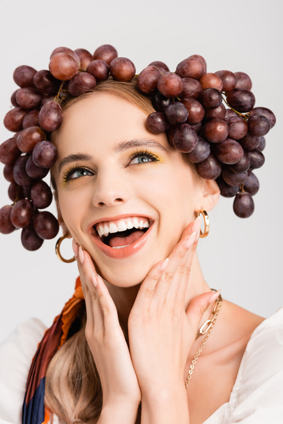 rustic blonde woman with grapes on head laughing isolated on white - 写真・画像