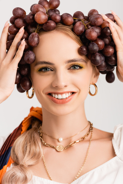 portrait of rustic blonde woman posing with grapes on head isolated on white - 写真・画像