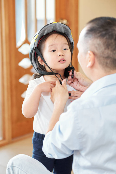 В "єтнамський чоловік просить доньку відкинути голову, коли він прив" яже їй шолом. - Фото, зображення