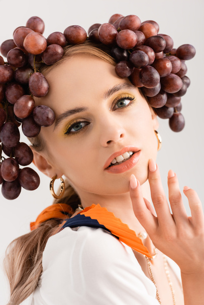 portrait of rustic blonde woman posing with grapes on head isolated on white - 写真・画像