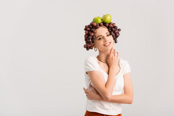 rustic blonde woman posing with grapes and apples on head isolated on white - 写真・画像