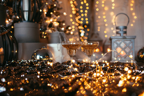 Dvě sklenice šampaňského nad rozmazanými skvrnami osvětluje pozadí. Koncept oslavy, volný prostor pro text. Zlatý dekor - Fotografie, Obrázek