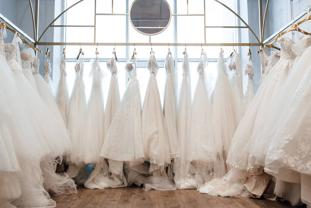 gyönyörű fehér esküvői ruhák vállfán a boltban - Fotó, kép